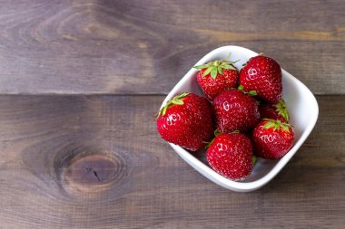 Çilek koyu ahşap arka plan üzerinde. Bahçe çilek.