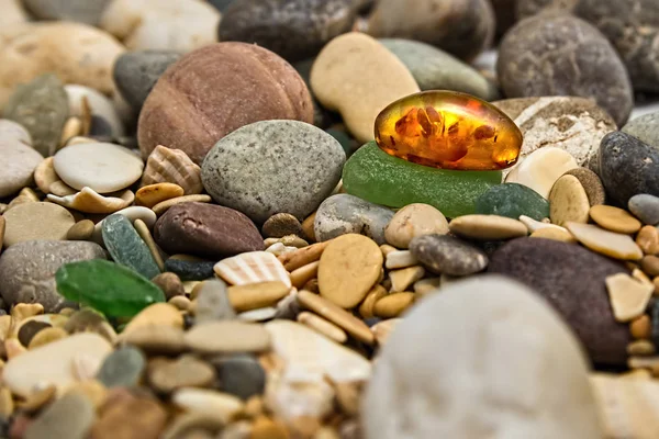 Amber stone. Mineral amber. Rosin yellow amber. Sunstone on a beach of pebbles.