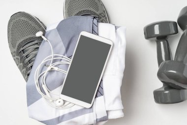 Spor malzemeleri ve cep telefonu maketi. Spor malzemeleri, cep telefonu ve beyaz arka planda egzersiz planı için boş alan