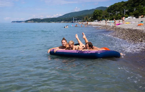 Familie drijvend op een luchtbed in de zee — Stockfoto