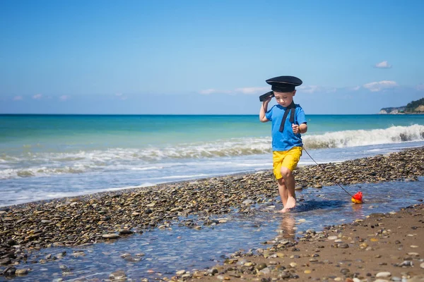 Baby boy with toy boat near sea — Stock Photo, Image