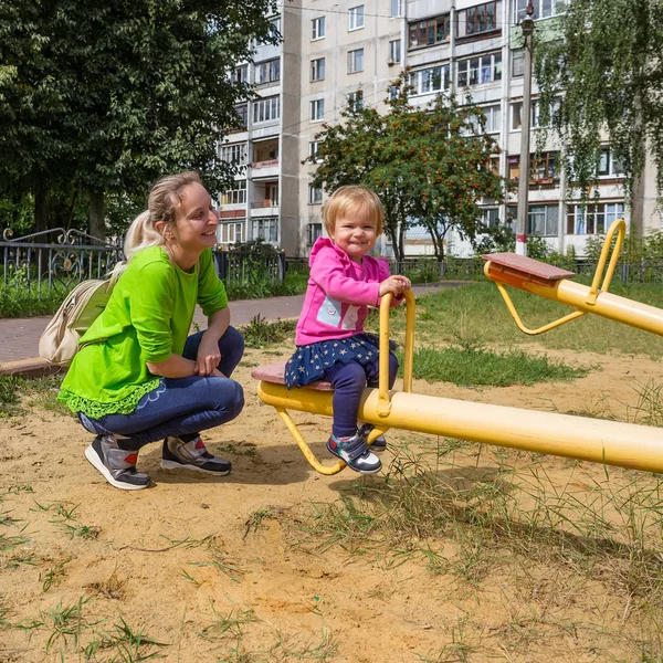Довольные дочь и мать на качелях на детской площадке — стоковое фото