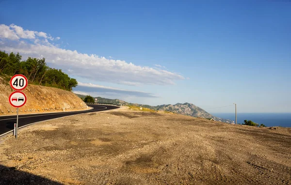 Signs on turn of road in mountains over the sea — Stock Photo, Image