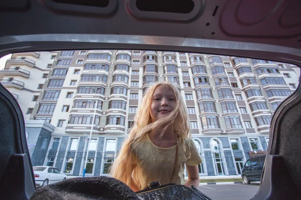 Meisje op zoek in de kofferbak van een auto — Stockfoto