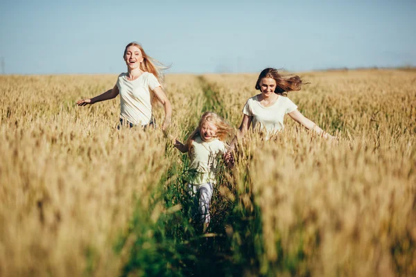 Madre e hijos corren sobre trigo archivado —  Fotos de Stock