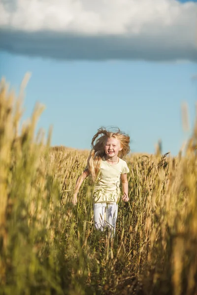 Glückliches süßes Mädchen spielt im Weizenfeld — Stockfoto