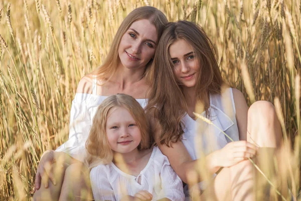 Hermosa madre joven y sus hijas en el campo de trigo — Foto de Stock