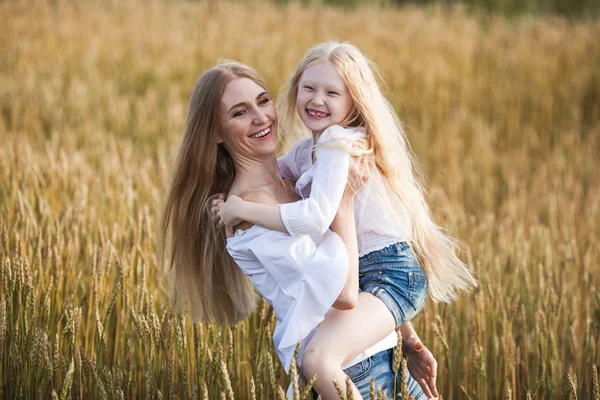 Beautiful young mother and her daughter at the wheat field — Stock Photo, Image