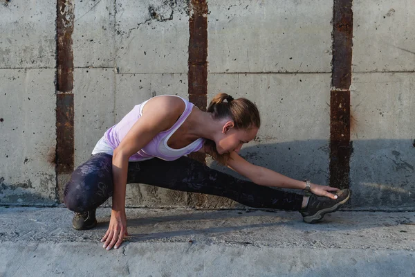 Porträtt av en ung fitness kvinna stretching utomhus — Stockfoto