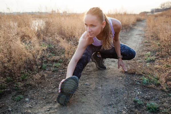 Jovem mulher se alongando antes de correr ao ar livre — Fotografia de Stock