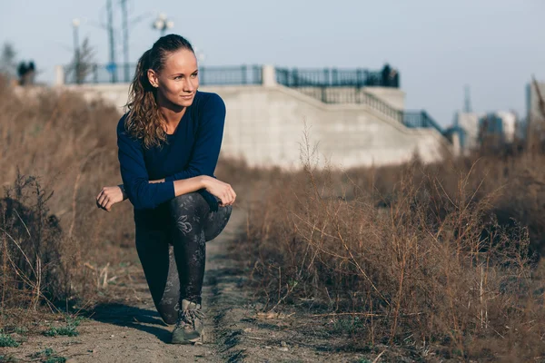 Jonge vrouw die zich uitstrekt voordat haar lopen buiten — Stockfoto