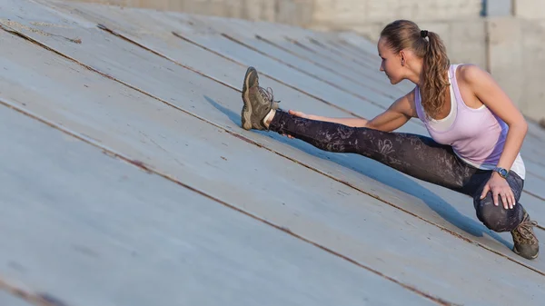 Retrato de uma jovem mulher fitness que se estende ao ar livre — Fotografia de Stock