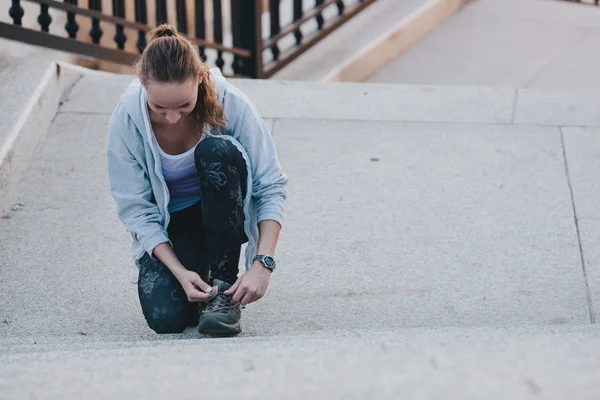 Portrait of a young exercise woman tying her shoelaces — Stock Photo, Image