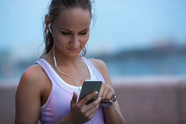 Jeune femme sportive sportive utilisant son smartphone le soir — Photo