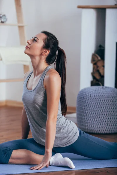Joven mujer sonriente atractiva practicando yoga en casa —  Fotos de Stock