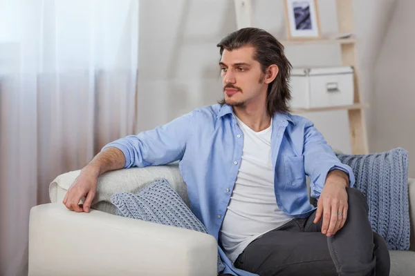 Jovem sentado no sofá em casa — Fotografia de Stock