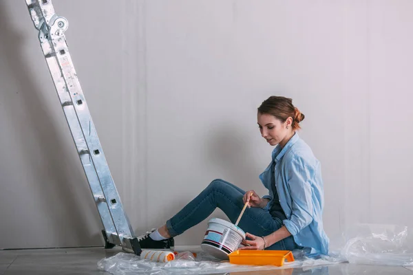Woman sitting on the floor and mixing wall paint — Stock Photo, Image