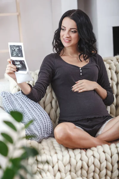 Boldog szép terhes nő pihentető a kanapéra echo kezében — Stock Fotó