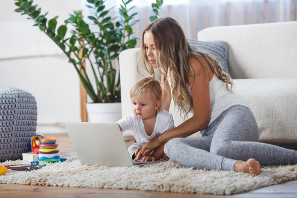 Neşeli küçük çocuk ve annesi oynarken yerde yatarken dizüstü bilgisayarda oyun — Stok fotoğraf