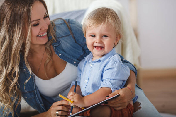 happy mom with son drawing on the floor