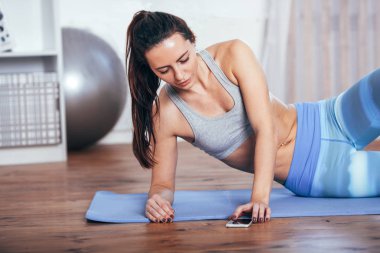 Smartphone ile evde egzersiz yaparak ince fitness genç kadın