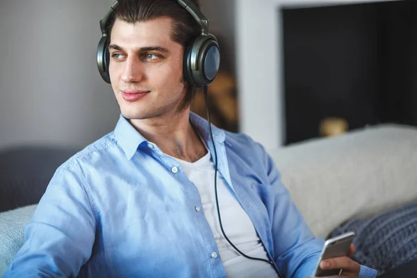 Bonito cara sentado no sofá com fones de ouvido — Fotografia de Stock