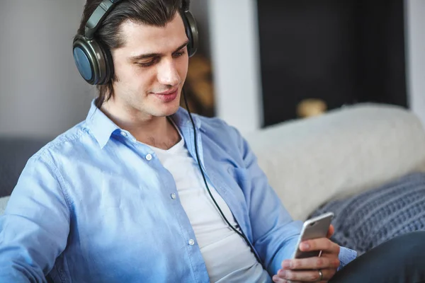 Bonito cara sentado no sofá com fones de ouvido — Fotografia de Stock