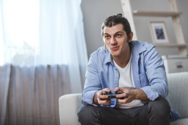 genç adam onun oda içinde video oyunları oynarken bir kanepede oturmuş