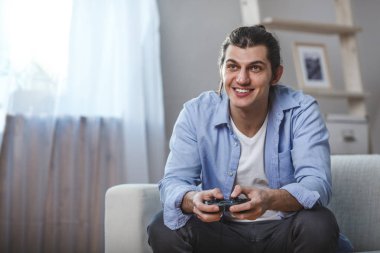 genç adam onun oda içinde video oyunları oynarken bir kanepede oturmuş
