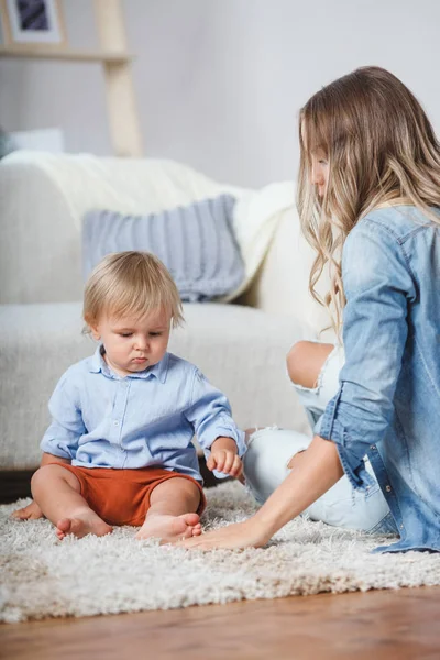 Madre e figlio giocano sul tappeto vicino al divano — Foto Stock