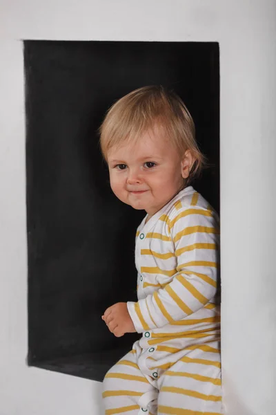 Retrato de sorrindo menino bonito no nicho parede preta — Fotografia de Stock