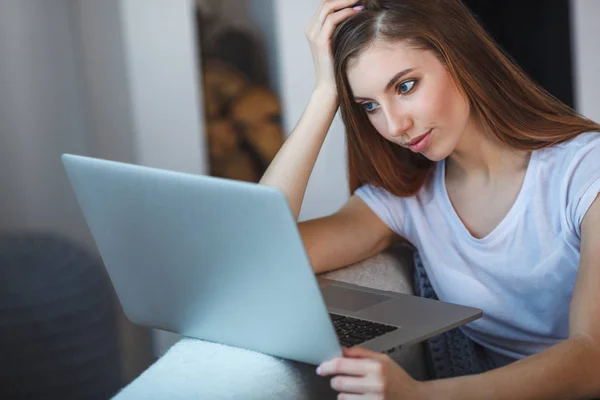 Mujer joven sentada con el ordenador portátil en el sofá en su casa —  Fotos de Stock