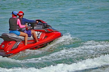 Miami Beach kapalı Florida iç kıyı su yolu üzerinde bir kırmızı Jet Ski tandem sürme genç bir çift yakın.