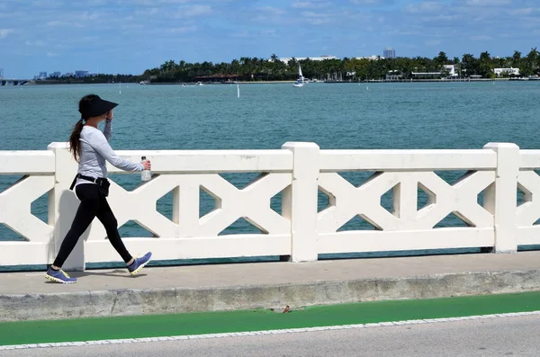 Young woman power walking on the Venetia Causeway in Miami Beach,Florida