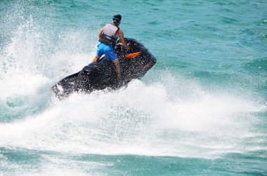 Genç adam siyah bir jet ski ile hız yapıyor.