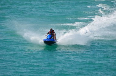 Genç çift hızla giden bir jetski 'ye biniyor.