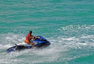 Young woman riding on a jet ski on the Florida Intra-Coastal Waterway off Miami Beach. clipart