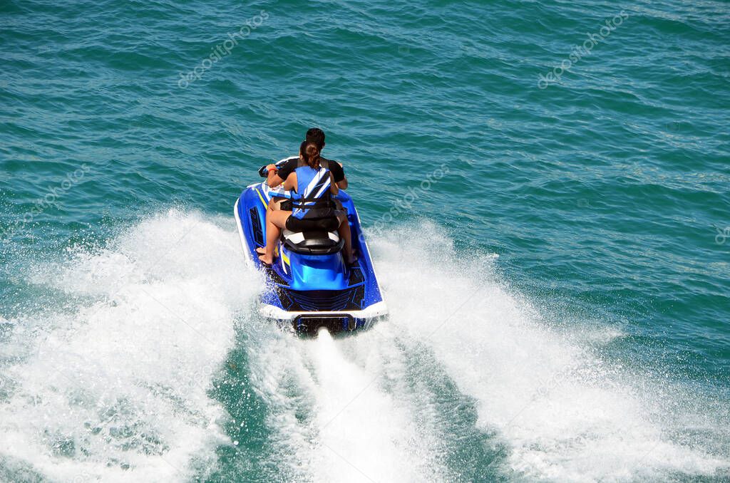 Young boy and girl riding tandem on a speeding jet ski.