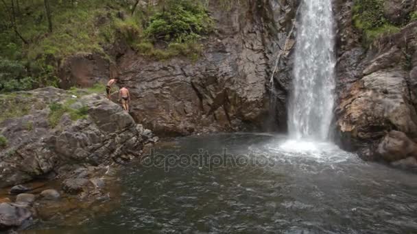 Män som simmar i floden nära waterfall — Stockvideo