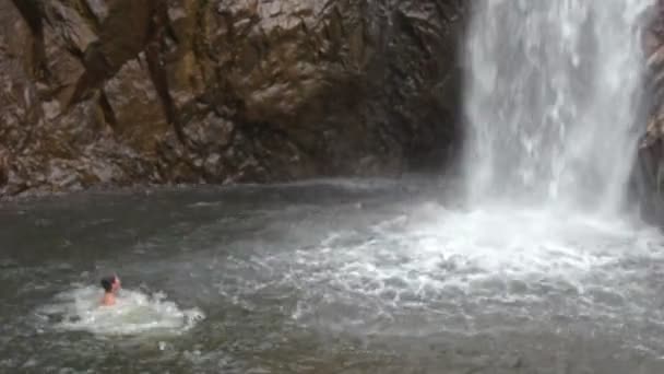Man simmar i floden nära waterfall — Stockvideo