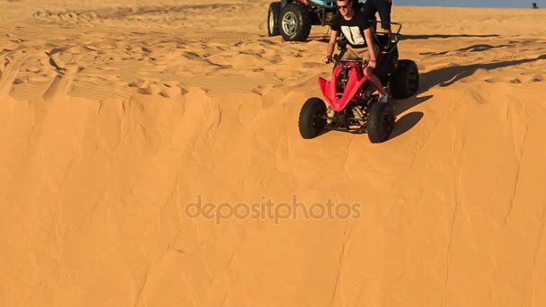 Tourists run quads down white sand dune — Stock Video
