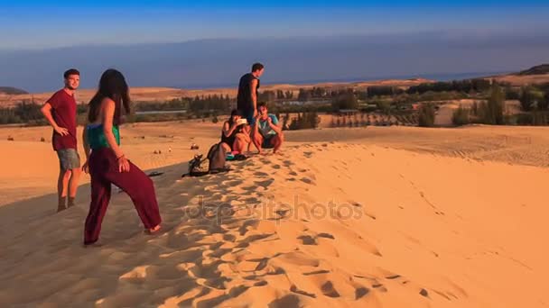 Парни и девушки скользят из песчаной дюны — стоковое видео