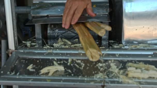 Homem desenha haste de cana-de-açúcar fora da máquina de fabricação de suco — Vídeo de Stock