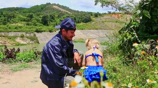 Padre se pone en cuclillas con hija con se quita la gorra — Vídeos de Stock