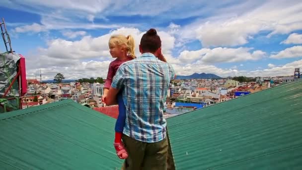 Father with daughter walks on roof against city — Stock Video