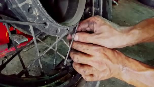 Um homem está reparando uma roda em sua motocicleta — Vídeo de Stock