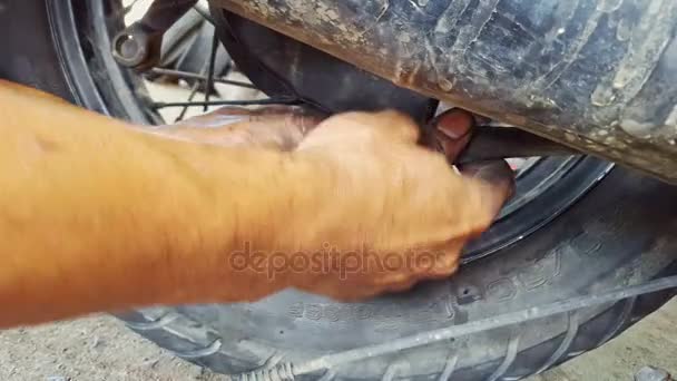 Un hombre está reparando una rueda en su motocicleta — Vídeo de stock