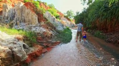 Closeup arka baba küçük kız yürümek akışında taşlı banka tarafından