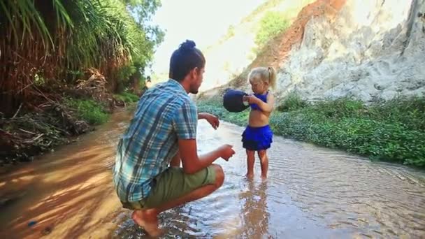 Padre ocupa hija juega con tapa en agua corriente de hadas — Vídeos de Stock