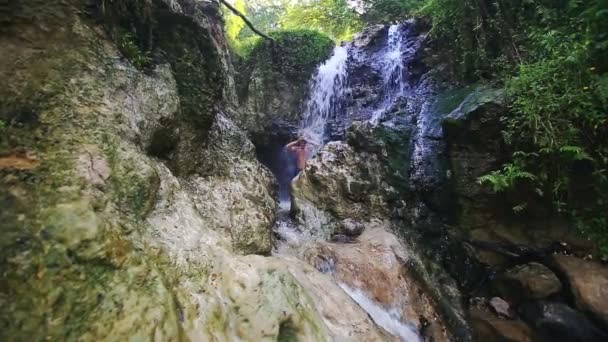 Primo piano uomo bagna sotto cascata getti tra le rocce — Video Stock